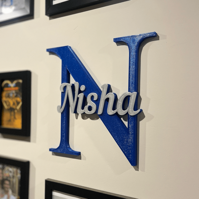 A personalised 3D printed name in blue and silver, on a wall